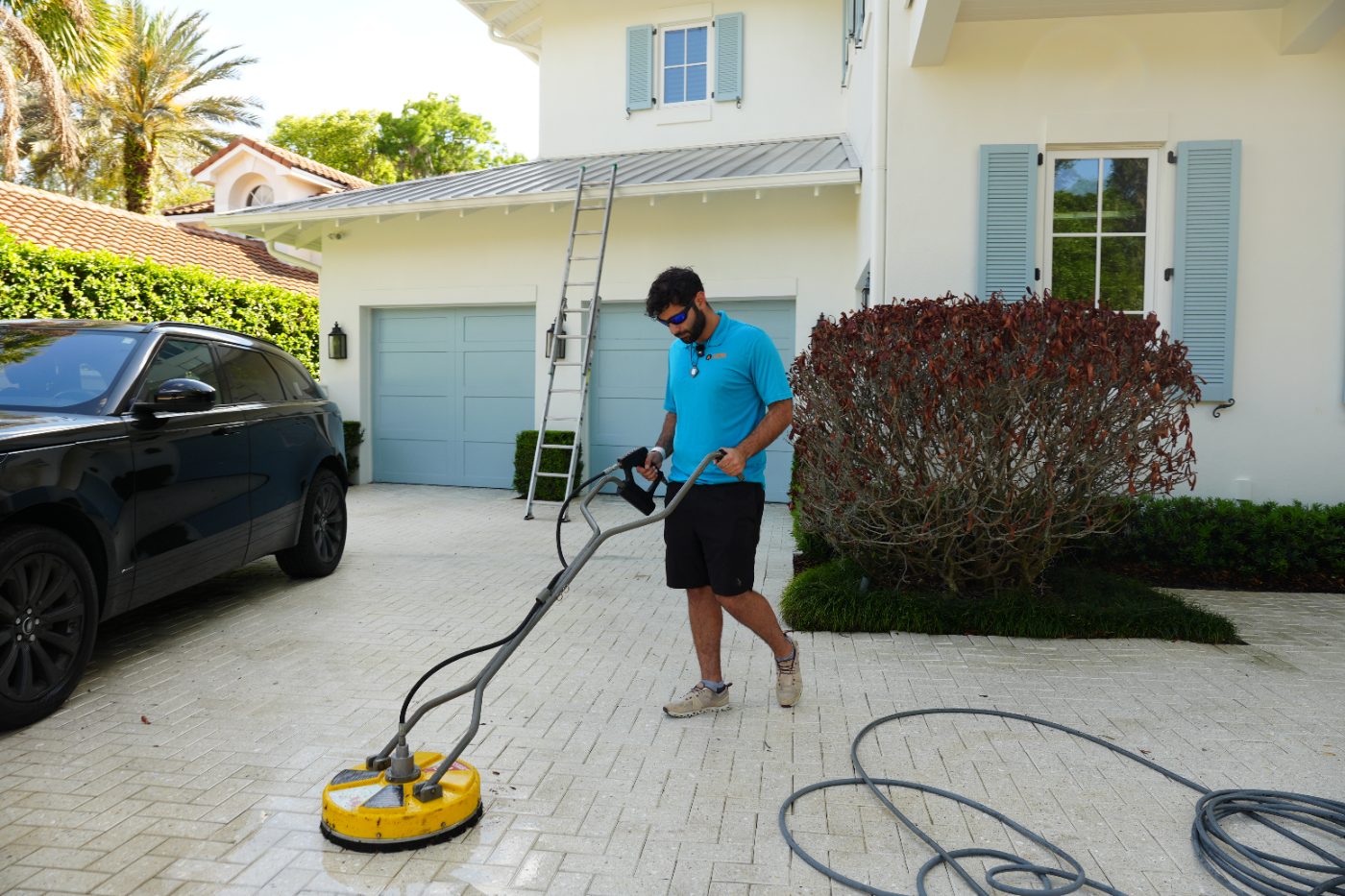 Pressure washer wand rinsing a concrete driveway