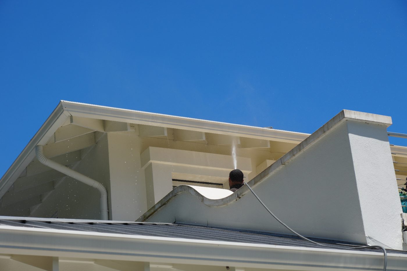 Hand cleaning a shingled roof with a brush