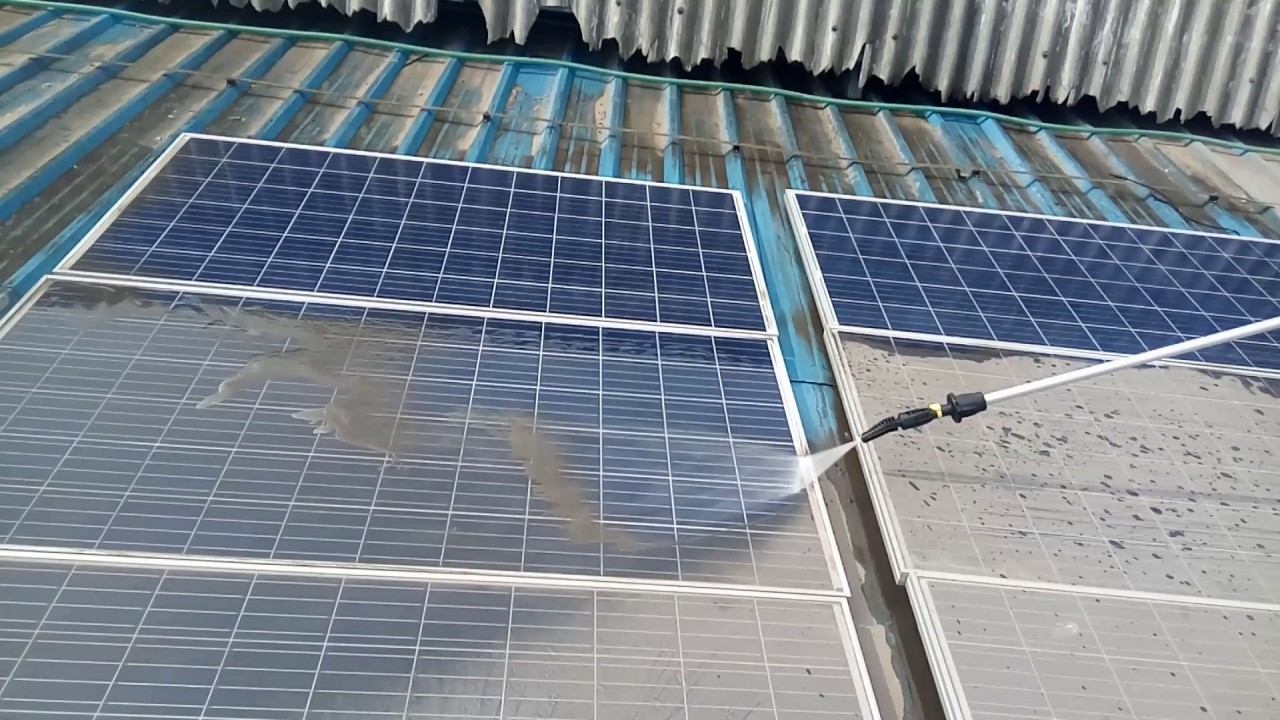 Gloved hands wiping a solar panel